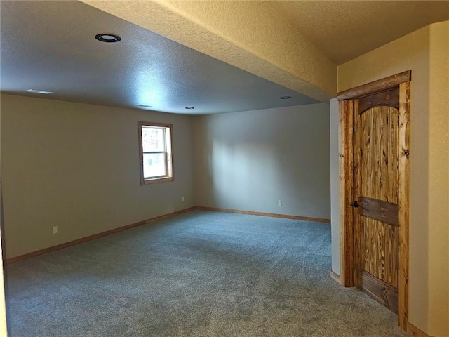 spare room with a textured ceiling, carpet flooring, and baseboards