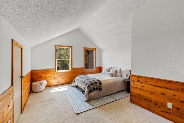 524 Buena Vista Ct, Steamboat Springs, CO 80487 - bedroom featuring a textured ceiling, carpet, wood walls, lofted ceiling, and wainscoting