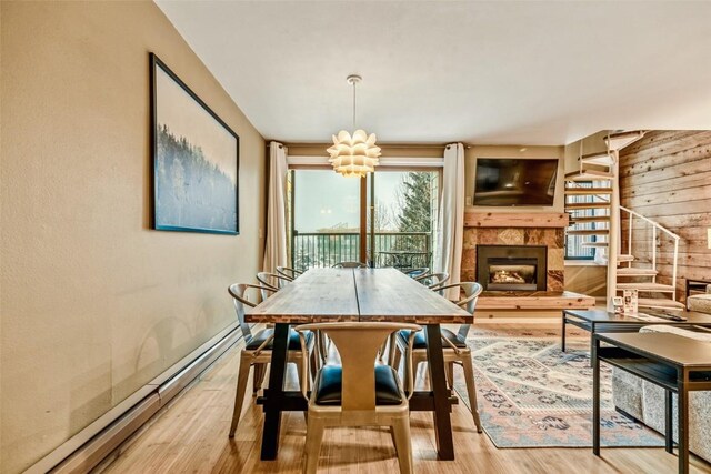 165 Argentine Ct Unit 1407, Keystone, CO 80435 - dining room featuring a baseboard radiator, wood finished floors, a tile fireplace, wood walls, and a chandelier