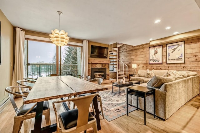 living area with recessed lighting, wood walls, a fireplace with raised hearth, and light wood-style flooring