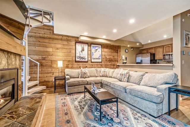 living area featuring wooden walls, recessed lighting, wood finished floors, stairway, and a tile fireplace