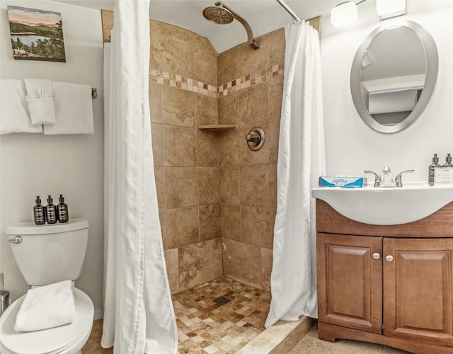 bathroom featuring a tile shower, toilet, and vanity