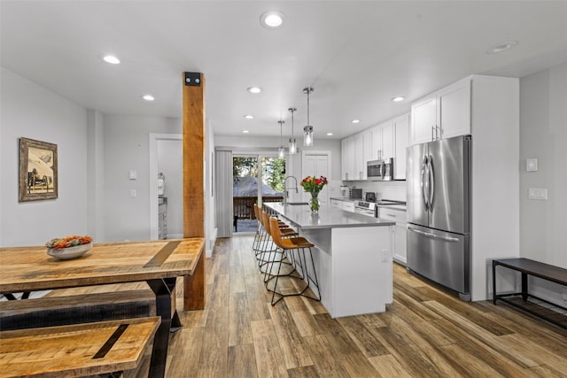 112 Illinois Gulch Rd Unit 6, Breckenridge, CO 80424 - kitchen with a kitchen breakfast bar, wood finished floors, a center island with sink, appliances with stainless steel finishes, and recessed lighting
