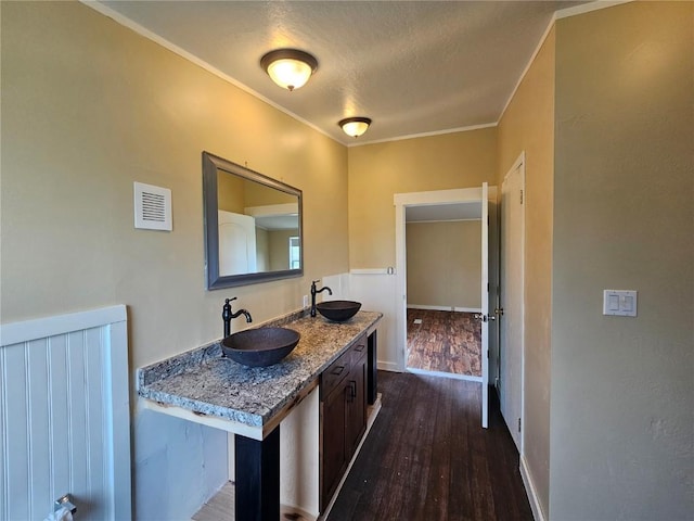 21762 4th Ave, Phippsburg, CO 80469 - bathroom featuring wood finished floors, a textured ceiling, double vanity, ornamental molding, and baseboards