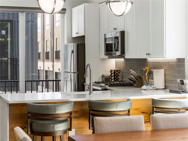 62 W 3rd St Unit D, Silverthorne, CO 80498 - kitchen with stainless steel appliances, tasteful backsplash, light countertops, a breakfast bar area, and white cabinets