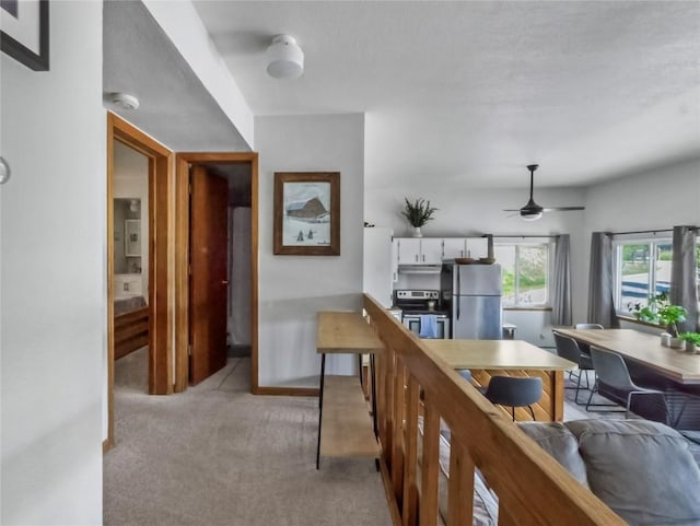 9876 Ryan Gulch Rd Unit 106, Silverthorne, CO 80498 - kitchen with stainless steel appliances, white cabinetry, under cabinet range hood, light colored carpet, and a ceiling fan