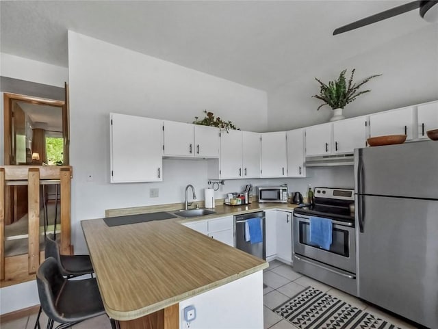 9876 Ryan Gulch Rd Unit 106, Silverthorne, CO 80498 - kitchen with appliances with stainless steel finishes, a sink, under cabinet range hood, white cabinets, and a peninsula