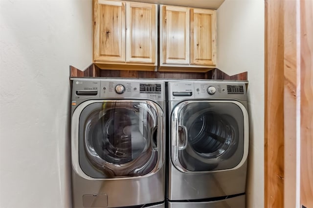 washroom featuring washing machine and dryer and cabinet space