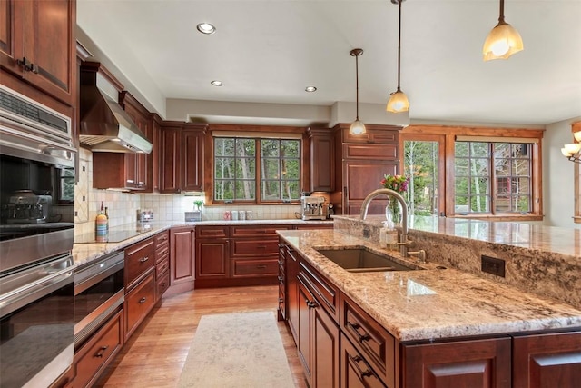 168 Corkscrew Dr, Breckenridge, CO 80424 - kitchen featuring a sink, wall chimney exhaust hood, appliances with stainless steel finishes, tasteful backsplash, and light wood finished floors