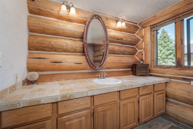 23125 Fawn Creek Rd, Steamboat Springs, CO 80487 - bathroom with log walls, vanity, and a textured wall