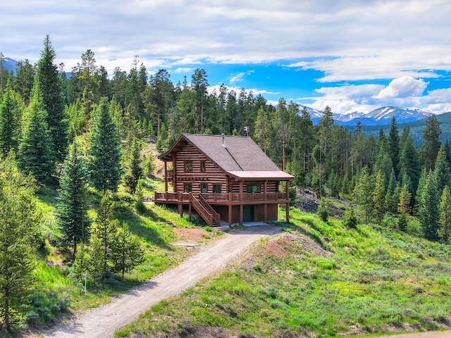 922 Braddock Dr, Breckenridge, CO 80424 - back of property featuring log exterior, a forest view, a deck with mountain view, dirt driveway, and stairway