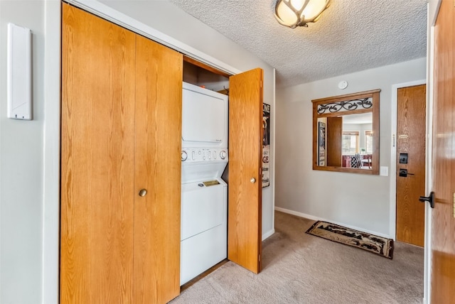 interior space with baseboards, stacked washer and clothes dryer, a textured ceiling, and carpet flooring