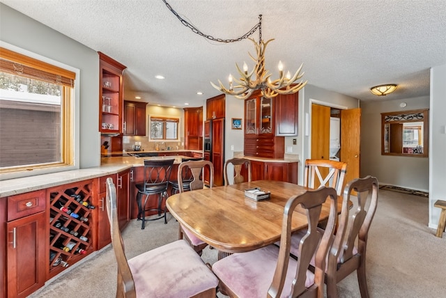 dining area with plenty of natural light, a textured ceiling, light carpet, and an inviting chandelier