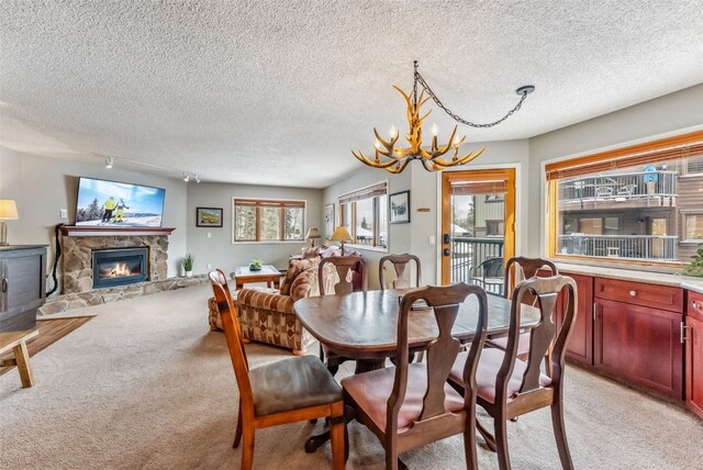 dining space featuring a fireplace, a textured ceiling, light colored carpet, and a notable chandelier