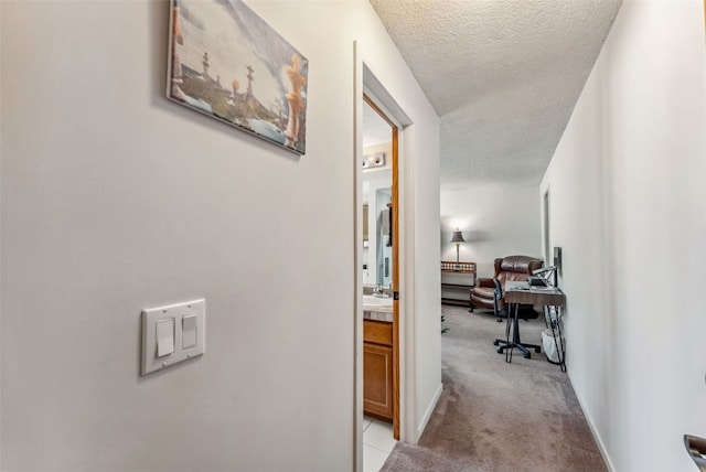 hallway with light carpet and a textured ceiling