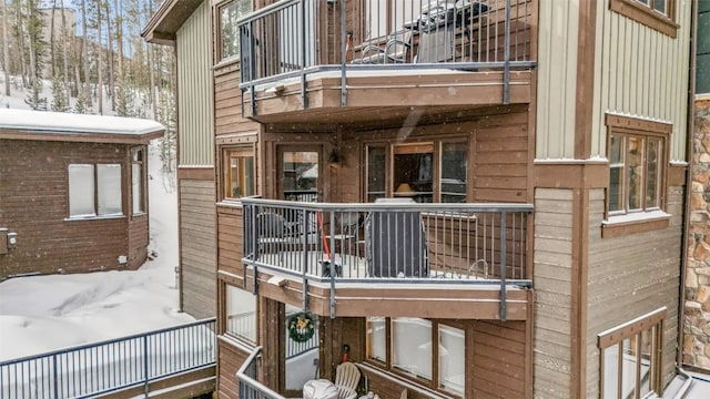 snow covered back of property featuring a balcony