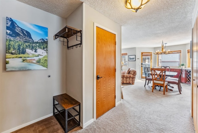 hall featuring a chandelier, carpet, a textured ceiling, and baseboards