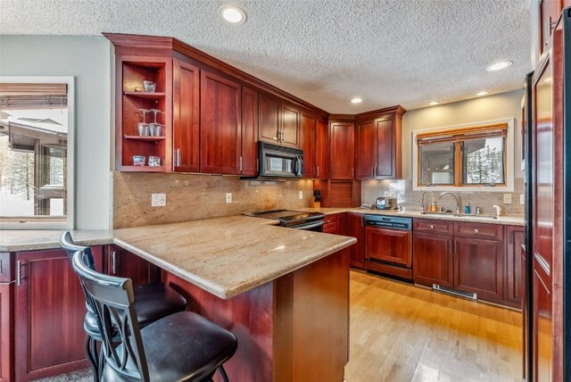 kitchen featuring paneled dishwasher, a sink, plenty of natural light, reddish brown cabinets, and black microwave