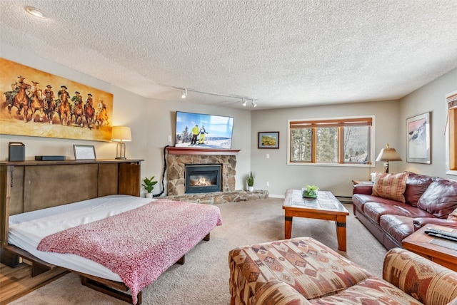 carpeted living area featuring baseboards, a fireplace, a textured ceiling, and rail lighting