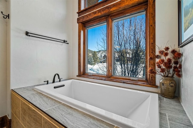 bathroom with plenty of natural light and tiled tub