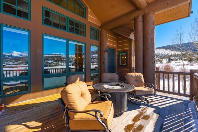 snow covered deck featuring an outdoor fire pit and a mountain view