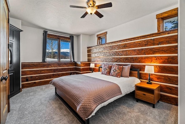 bedroom featuring ceiling fan, a textured ceiling, and dark colored carpet