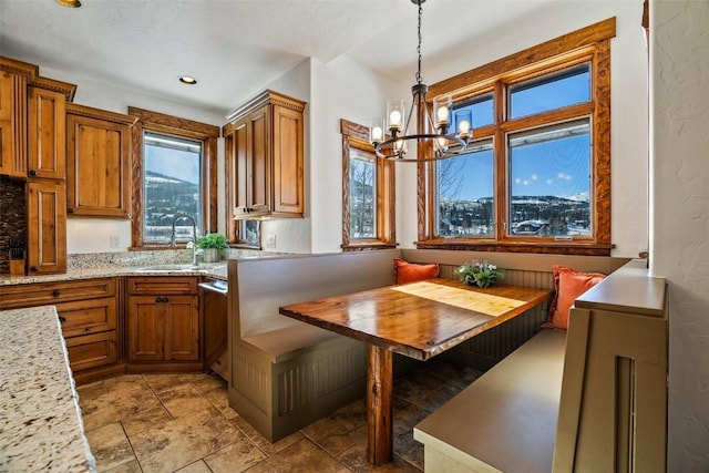 kitchen with light stone countertops, pendant lighting, breakfast area, dishwasher, and sink