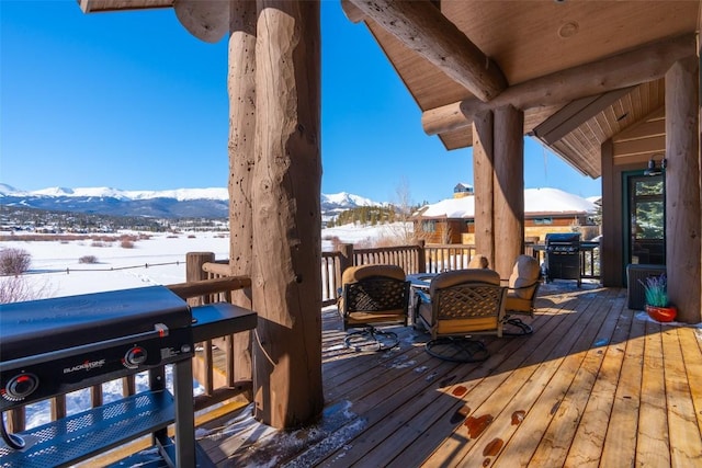 snow covered deck with a mountain view and area for grilling