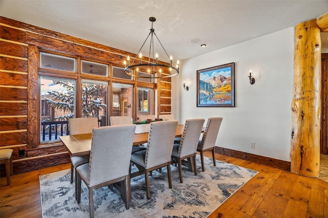 dining area with dark wood-type flooring and an inviting chandelier