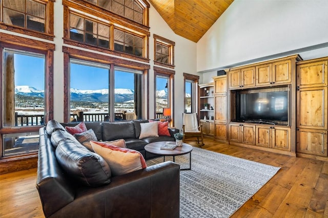 living room with a mountain view, wooden ceiling, high vaulted ceiling, and light wood-type flooring