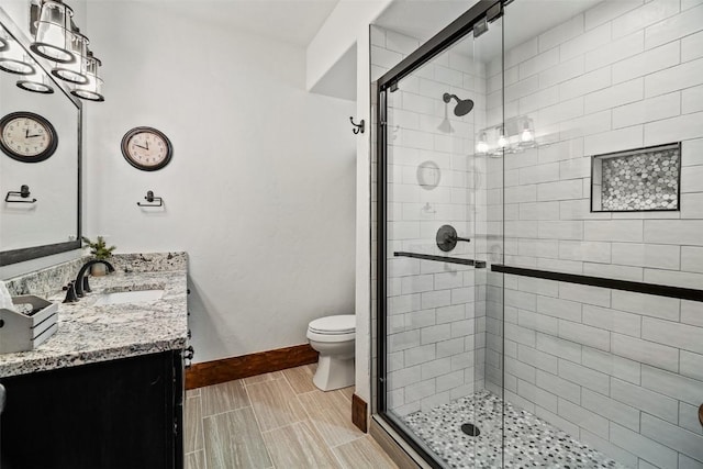 bathroom featuring toilet, a shower with shower door, and vanity