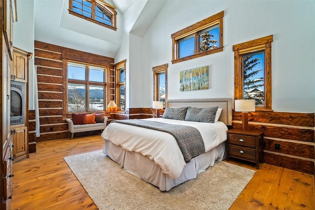 bedroom featuring a towering ceiling and light wood-type flooring