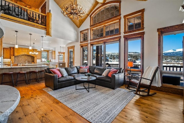 living room featuring a mountain view, wooden ceiling, a notable chandelier, light wood-type flooring, and high vaulted ceiling