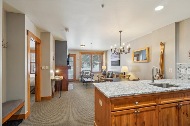 53 Hunki Dori Ct Unit 8806, Keystone, CO 80435 - kitchen featuring a peninsula, a sink, a notable chandelier, light colored carpet, and brown cabinetry