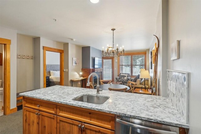 53 Hunki Dori Ct Unit 8806, Keystone, CO 80435 - kitchen with a sink, brown cabinets, dishwasher, carpet floors, and a notable chandelier
