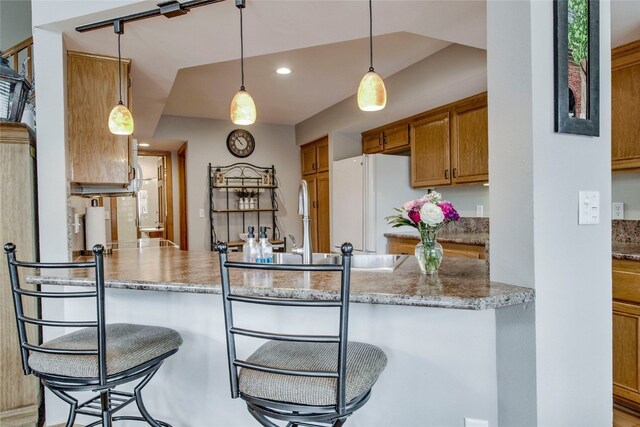 116 Blue Grouse Ln, Silverthorne, CO 80498 - kitchen with brown cabinets, a peninsula, pendant lighting, freestanding refrigerator, and recessed lighting