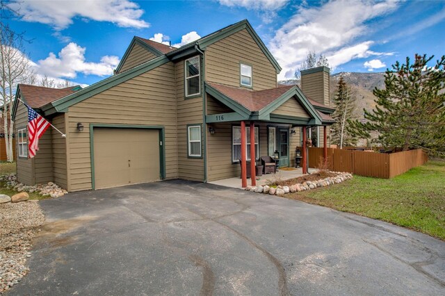 116 Blue Grouse Ln, Silverthorne, CO 80498 - view of front facade featuring a porch, a garage, asphalt driveway, and a chimney