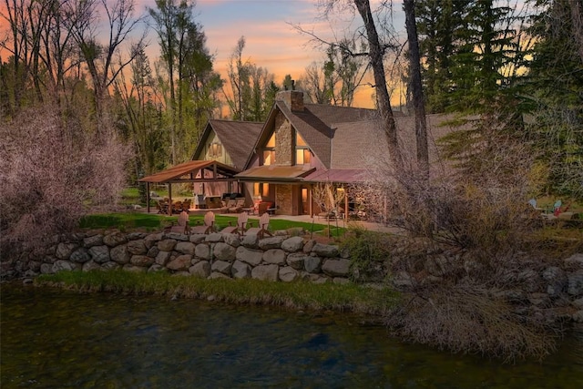 44 Maverick Way, Silverthorne, CO 80498 - back of house at dusk with a chimney, a patio area, a water view, and a shingled roof