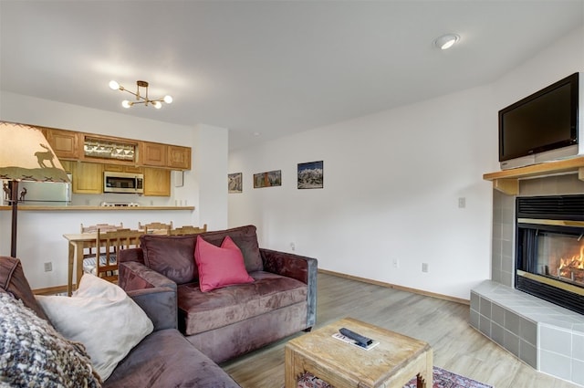 400 Bayview Dr Unit D, Frisco, CO 80443 - living room featuring wood finished floors, a tiled fireplace, a chandelier, and baseboards