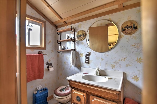 half bath featuring wallpapered walls, vaulted ceiling, toilet, and vanity