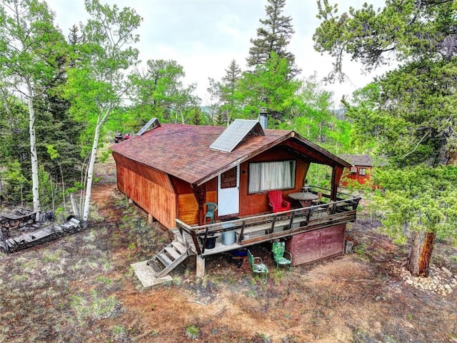 rear view of house with roof with shingles and solar panels