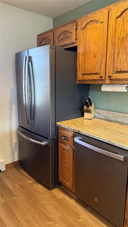 9430 Ryan Gulch Rd Unit 9453, Silverthorne, CO 80498 - kitchen featuring appliances with stainless steel finishes, light wood-style flooring, brown cabinets, and light stone countertops