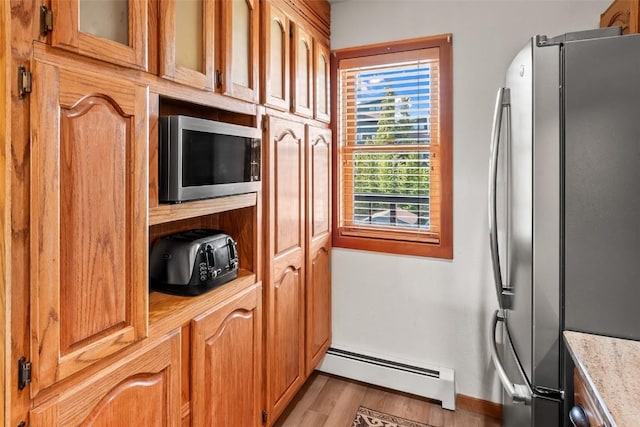 9430 Ryan Gulch Rd Unit 9453, Silverthorne, CO 80498 - kitchen with appliances with stainless steel finishes, a baseboard radiator, light wood finished floors, baseboards, and brown cabinetry
