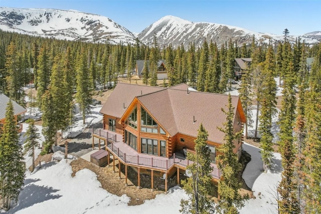 306 Robertson Ln, Breckenridge, CO 80424 - snow covered back of property featuring log siding, a deck with mountain view, a wooded view, and roof with shingles