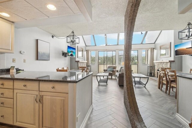 kitchen featuring recessed lighting, light brown cabinetry, dark stone countertops, a peninsula, and open floor plan