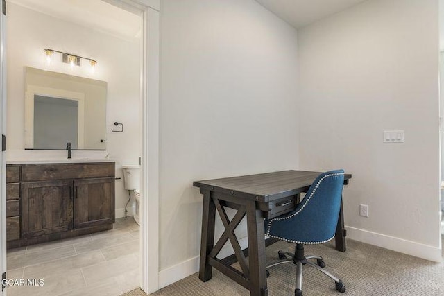 office featuring a sink, baseboards, and light colored carpet