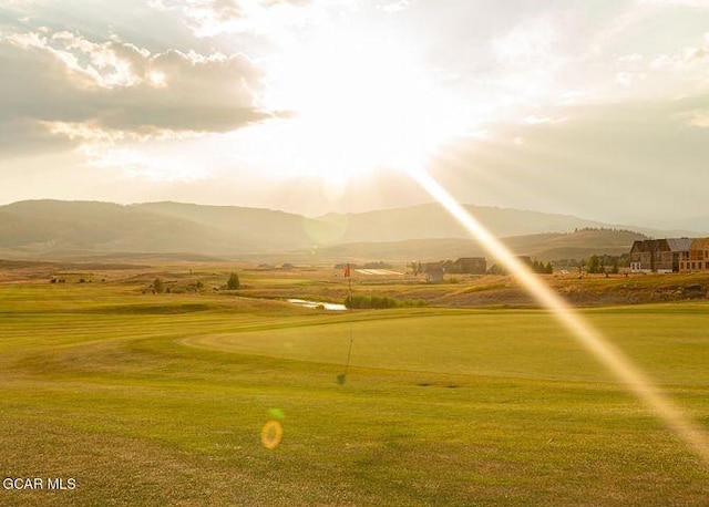 view of property's community featuring a yard, a mountain view, and view of golf course