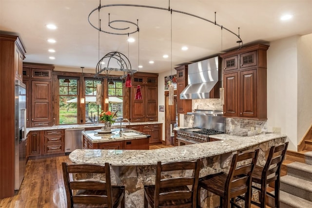 215 Royal Tiger Rd, Breckenridge, CO 80424 - kitchen featuring wall chimney range hood, recessed lighting, a kitchen island with sink, stainless steel appliances, and dark wood-type flooring