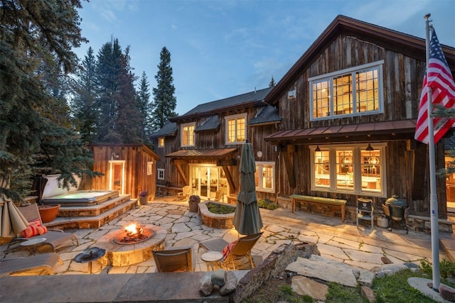 215 Royal Tiger Rd, Breckenridge, CO 80424 - rear view of house featuring a fire pit, a patio, a standing seam roof, a hot tub, and a metal roof