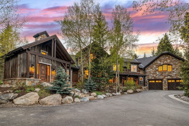 215 Royal Tiger Rd, Breckenridge, CO 80424 - view of front facade featuring stone siding, driveway, a garage, and a chimney